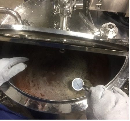 Boiling kettle filled with peach juice during sterilization.