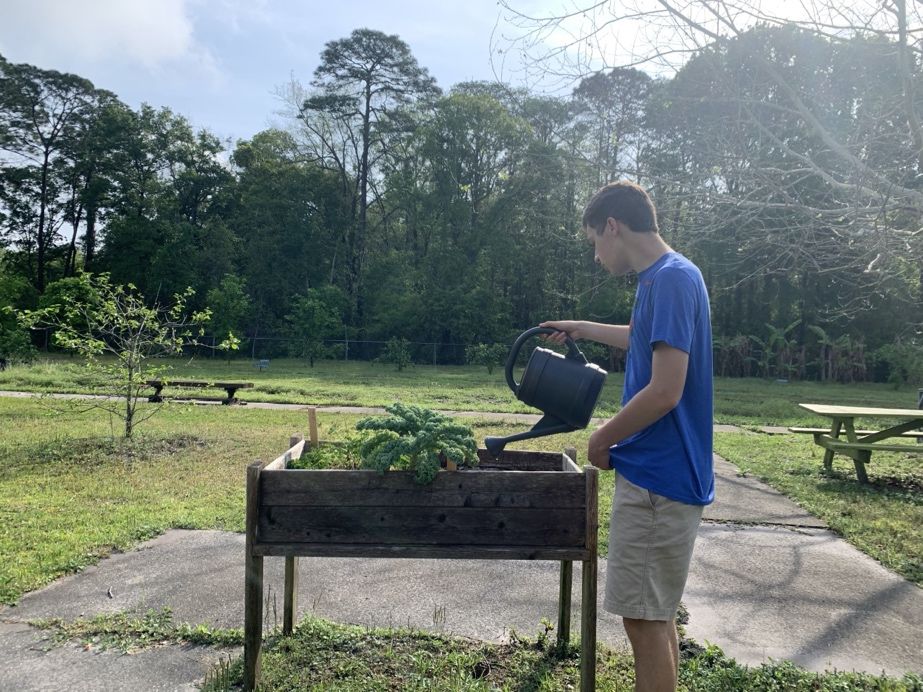 A student at the Growing Educational Training (GET) program in Gainesville, Florida, watering plants in an accessible garden. 